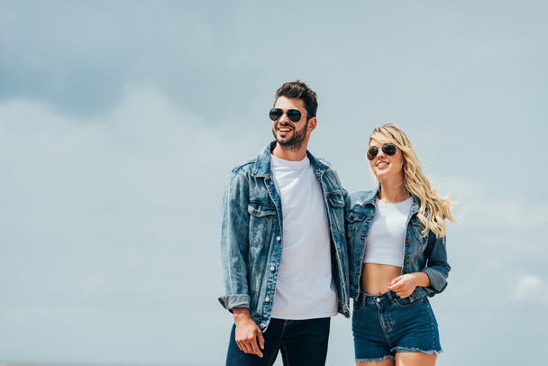 attractive woman and handsome man in denim jackets smiling and hugging outside  - Valokuva, kuva