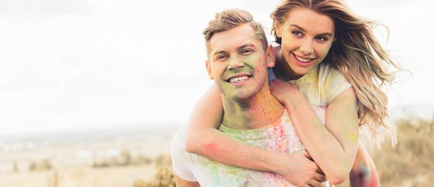panoramic shot of handsome man piggybacking his smiling and attractive girlfriend  - Photo, Image