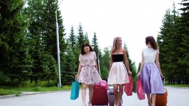 Τρεις πολλές εθνοτικές κοπέλες με βαλίτσες και σακούλες για ψώνια περπατούν στις διακοπές. - Πλάνα, βίντεο