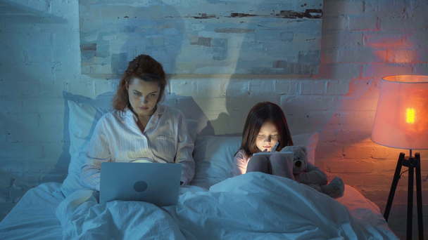 мати використовує ноутбук, а дочка використовує цифровий планшет у ліжку
 - Кадри, відео