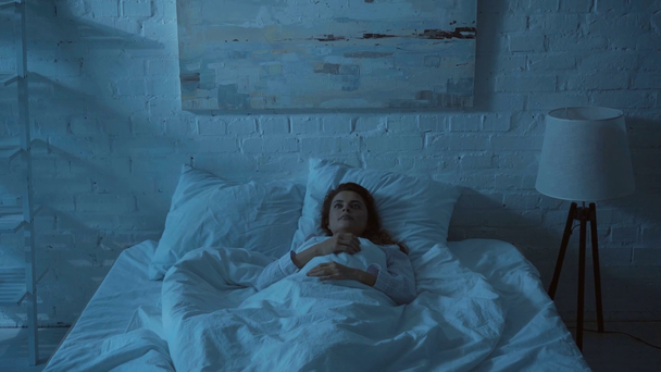 schläfrige erwachsene Frau gähnt und klatscht in die Hände, um die Beleuchtung auszuschalten - Filmmaterial, Video