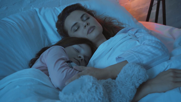 Äiti nukkuu tyttärensä kanssa sängyssä yöllä
 - Materiaali, video