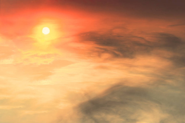 La puesta de sol en el cielo es rojo-naranja con nubes grises en forma de manchas en las que brilla el sol
. - Foto, imagen