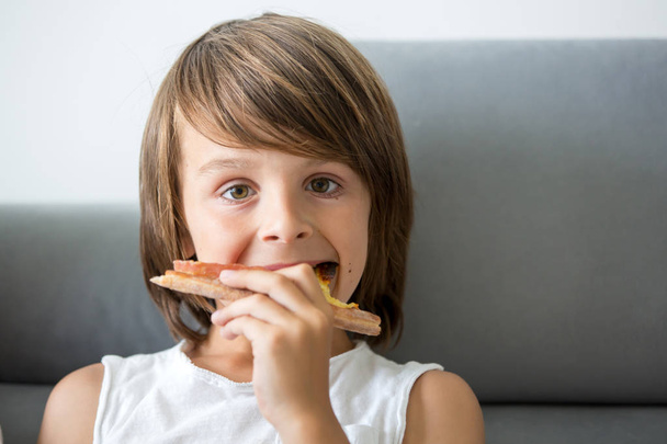 Cute little Caucasian kid eating pizza. Hungry child taking a bi - 写真・画像