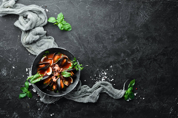 Tomato soup with seafood. Mussels, clams and octopuses. In the old background. Top view. Free copy space. - Foto, afbeelding