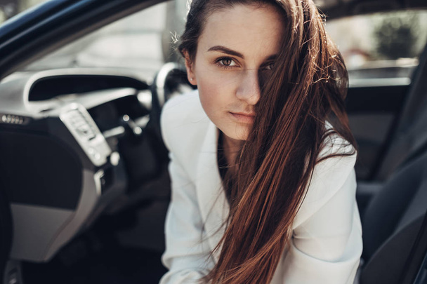 Mode stilvolles Mädchen im weißen Anzug posiert in der Nähe des blauen Autos - Foto, Bild