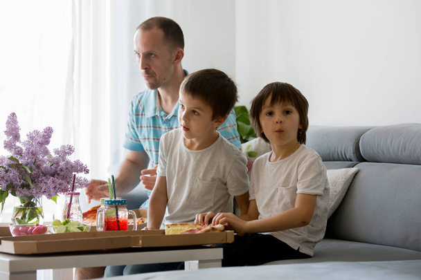 Father and his two boys, children, eating pizza at home and watc - Fotografie, Obrázek