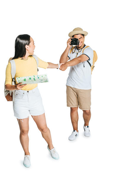 young asian tourist taking photo of girlfriend holding map on white background - Photo, Image