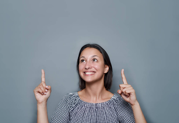 Woman pointing empty copy space on gray background - Photo, Image