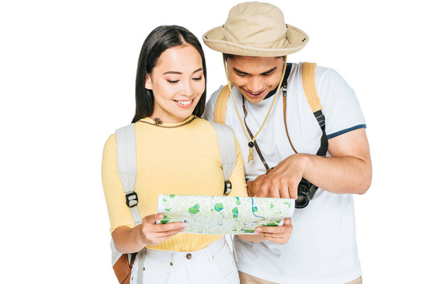 two young asian tourists smiling while looking at map isolated on white - Valokuva, kuva