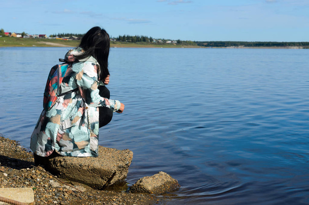 Das moderne traurige Mädchen Jakut blickt auf das Dorf Ulus suntar in der Nähe des Flusses vilyu, der mit Abfällen aus der Diamantenproduktion im Norden Russlands in Jakutien verseucht ist. - Foto, Bild