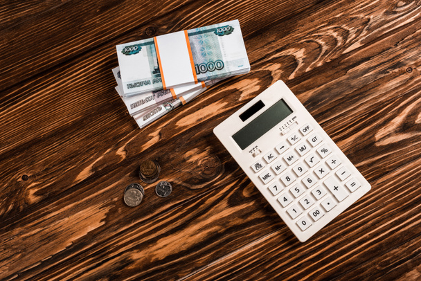 vista aérea de la calculadora blanca cerca del dinero ruso en la mesa de madera
  - Foto, Imagen