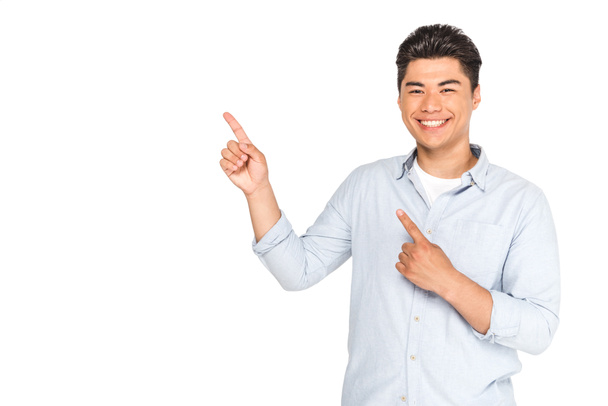 joven asiático hombre apuntando con los dedos mientras sonriendo a cámara aislado en blanco
 - Foto, imagen