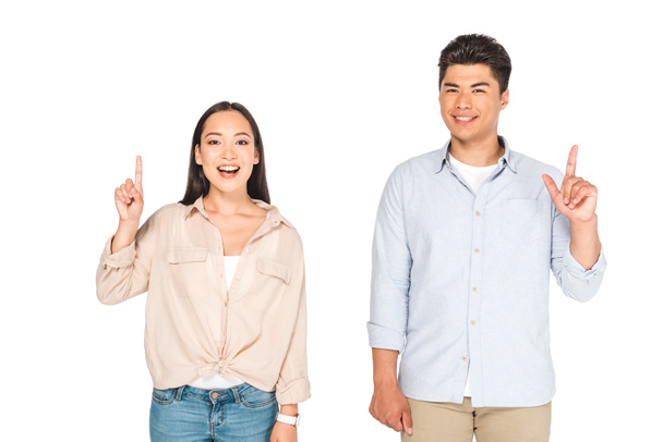 smiling asian man and woman showing idea signs while looking at camera isolated on white - Foto, Imagem