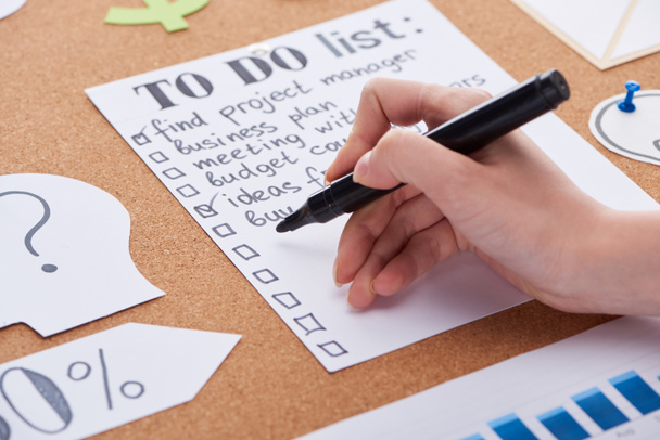 cropped view of woman writing with black highlighter on to do list on cork board - Photo, Image