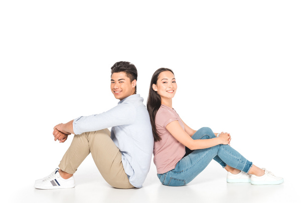 young asian couple sitting back to back and looking at camera on white background - Foto, immagini