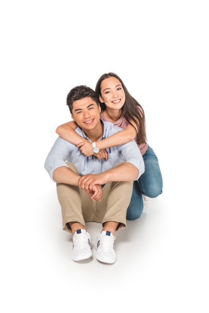 happy asian girl hugging boyfriend while sitting on white background - Foto, imagen