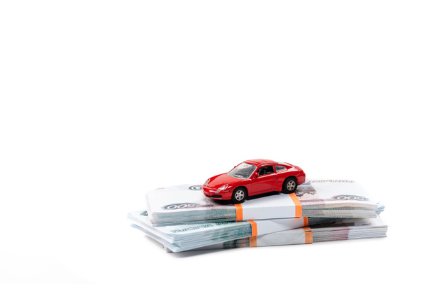 κόκκινο αυτοκίνητο παιχνίδι σε στοίβες των ρωσικών χρημάτων απομονώνονται σε λευκό  - Φωτογραφία, εικόνα