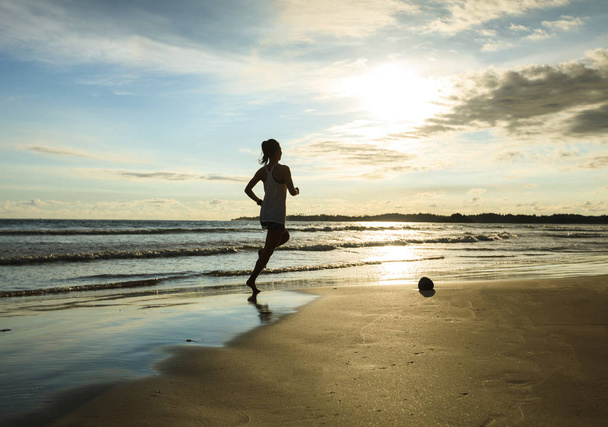 Fitness woman runner running on sunrise beach - Foto, imagen