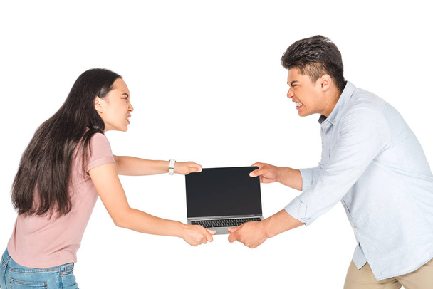 irritated asian man and woman holding laptop with blank screen isolated on white - Zdjęcie, obraz