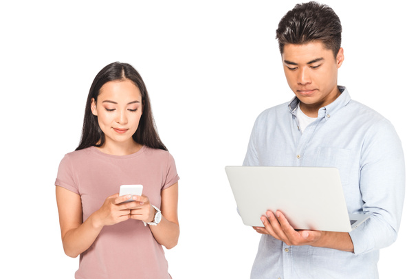 pretty asian woman using smartphone near boyfriend with laptop isolated on white - Photo, Image