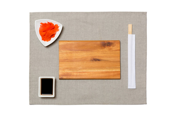 Üres téglalap alakú barna fa tányér pálcika a sushi, gyömbér és szójaszósz a szürke szalvéta háttérben. Felülnézet másolási területtel a tervezéshez - Fotó, kép