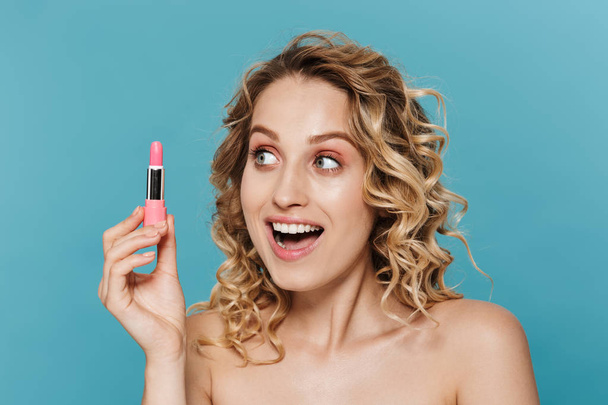 Image of amazed half-naked woman holding and looking at lipstick - Zdjęcie, obraz