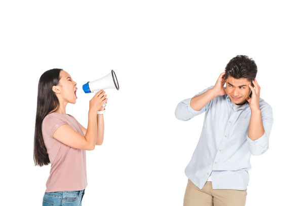 сердитая азиатская девушка кричит в мегафон на бойфренда, закрывая уши руками, изолированными на белом
 - Фото, изображение