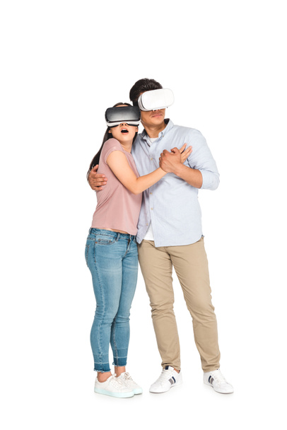 scared couple hugging while using virtual reality headsets on white background - Фото, изображение