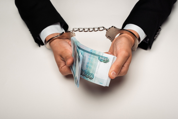 top view of businessman in handcuffs holding bribe on white  - Фото, зображення