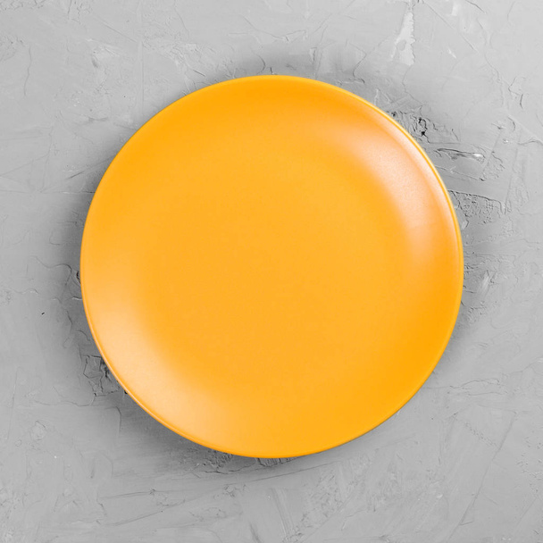 Placa redonda amarela no fundo da mesa de cimento cinza. Visão superior, modelo para o seu design
 - Foto, Imagem