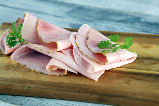 Sliced ham with parsley on table. Fresh prosciutto. Pork ham sli - Photo, Image