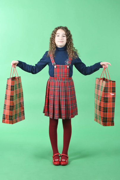 Παιδί με κόκκινο πακέτο απομονωμένο σε πράσινο φόντο. Μικρή Shopaholic ομορφιάς. Διακοπές σήμερα, ψώνια.  - Φωτογραφία, εικόνα