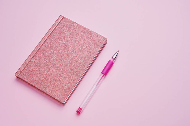 Bloc de notas rosa con bolígrafo sobre fondo rosa pastel. De vuelta al concepto escolar. Copiar espacio, vista superior
. - Foto, imagen