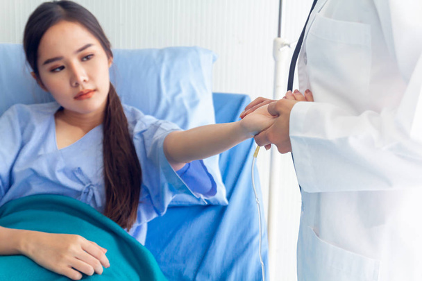 Aasialainen nuori naispotilas makaa sängyssä parantuneet oireet mahdollistavat lääkärin tarkistaa ja tallentaa hoidon tulokset
 - Valokuva, kuva