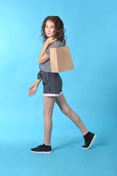 Enfant avec un paquet isolé sur fond bleu. Cadeau de vacances, shopping. Enfant heureux shopping dans le centre commercial
.  - Photo, image