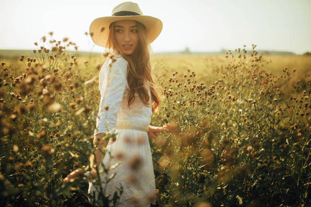 Красива молода жінка ходить серед квітів на лузі
. - Фото, зображення