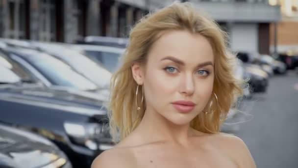 Portrait of a blonde with full lips and blue eyes on a background of parking - Séquence, vidéo