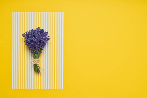 Bos van verse lavendel op geel gestreepte achtergrond. Bovenste weergave, kopieer ruimte. - Foto, afbeelding
