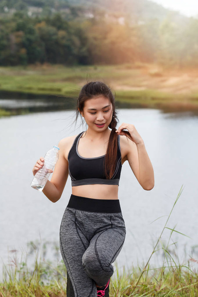 Attractive healthy fitness girl with fresh water after workout. Runner girl take a rest after training. - Photo, Image