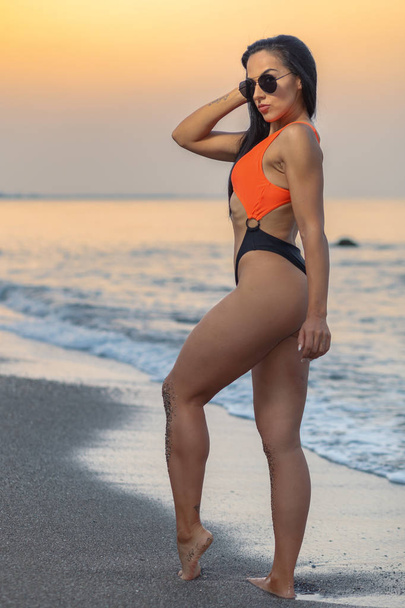 Fitness girl posing with a beautiful black and orange bikini - Zdjęcie, obraz