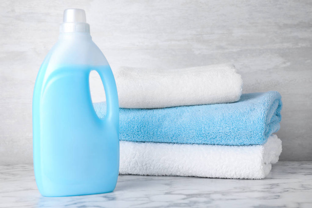 Bottle of laundry detergent and towels on marble table, space for text - Foto, Imagem