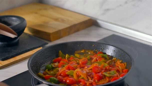 De kok roert de groenten in de pan met houten lepel. Slow Motion - Video