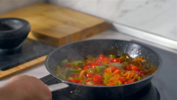 Koch arbeitet in der Küche, bunte Gemüsemischungen werden in der Pfanne gebraten. - Filmmaterial, Video
