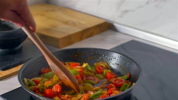 Der Koch rührt das Gemüse in der Pfanne mit einem Holzlöffel um. Zeitlupe - Filmmaterial, Video