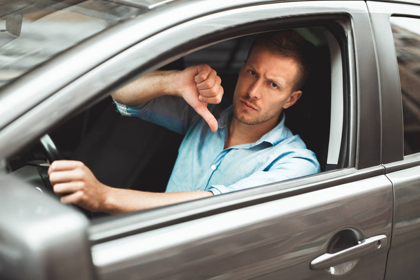 young handsome man sitting in his car showing dislike sign - Foto, afbeelding