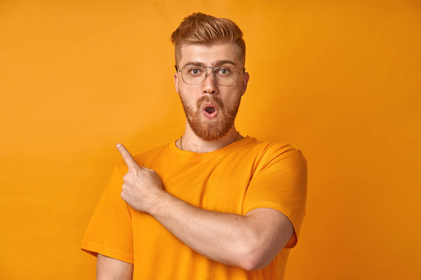 Surprised male with red beard, being stupefied as advertises something - Фото, изображение