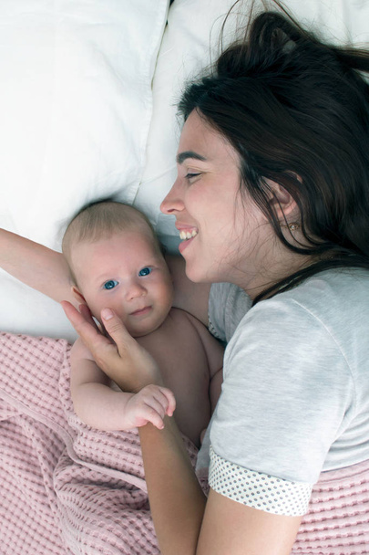 Beautiful brunette girl hugs and plays with baby. The concept of - 写真・画像