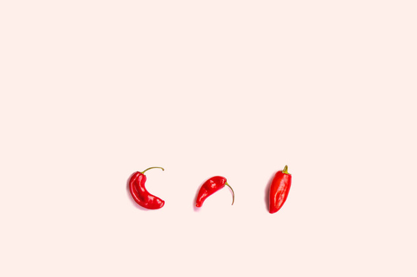 Ploché složení s červeným chilli papričkami na růžovém pozadí - Fotografie, Obrázek