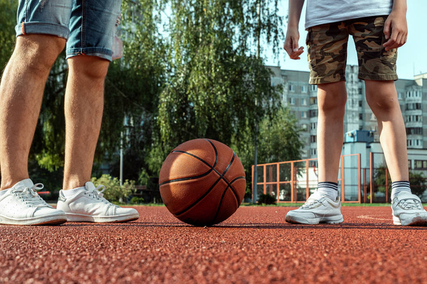 Father and son play basketball together at the basketball court. father spends time with the child, sporty lifestyle, training, rest, vacation. - 写真・画像
